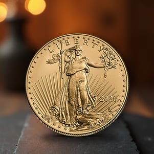 2026 1 oz Gold American Eagle coin featuring Lady Liberty standing with torch and olive branch, displayed upright on a dark slate surface with warm background lighting.