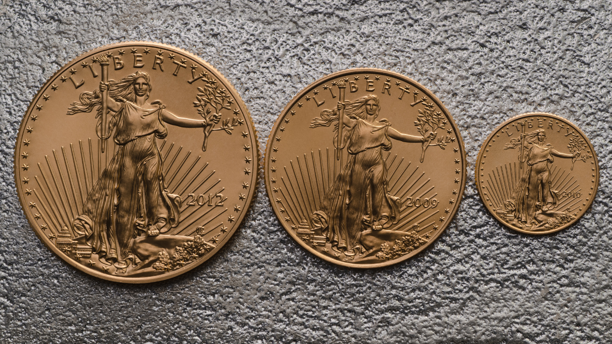 Three American Gold Eagle gold coins of different weights displaying the obverse Liberty design and dates