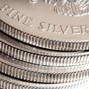 Close-up of stacked fine silver coins showing reeded edges and "Fine Silver" inscription on the top coin