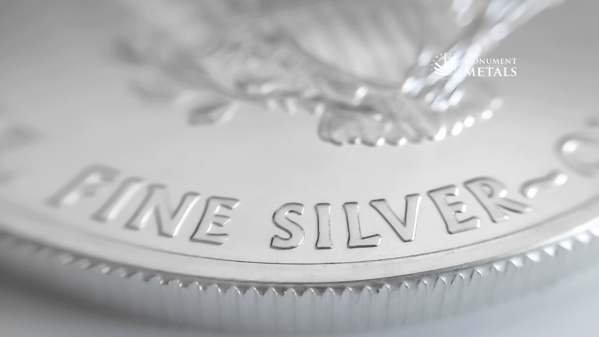 Close-up of an American Silver Eagle coin showing the "Fine Silver" inscription and eagle detail on the reverse