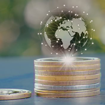 Stacked gold and silver coins with a digital global network overlay, representing global economic uncertainty and the worldwide precious metals market.