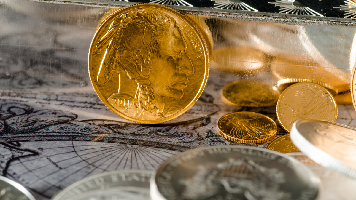 Gold Buffalo coin standing upright with gold bars and assorted silver bullion coins in foreground
