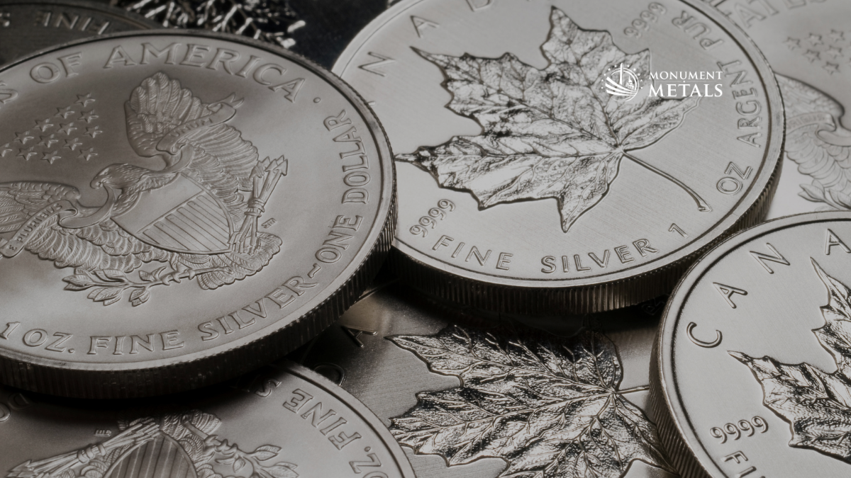 Close-up of government-issued silver bullion coins including American Silver Eagles and Canadian Maple Leafs showing detailed designs and .999+ fine silver purity, with Monument Metals logo.