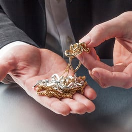 Hand holding silver and gold jewelry