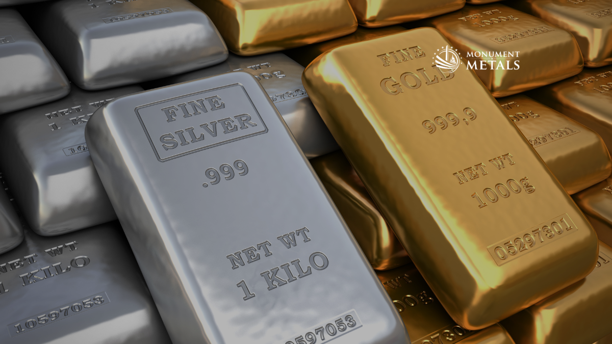 Stacked 1 kilo .999 fine silver bars alongside 1000g .9999 gold bars, highlighting large-format precious metals bullion, with the Monument Metals logo in the upper right.