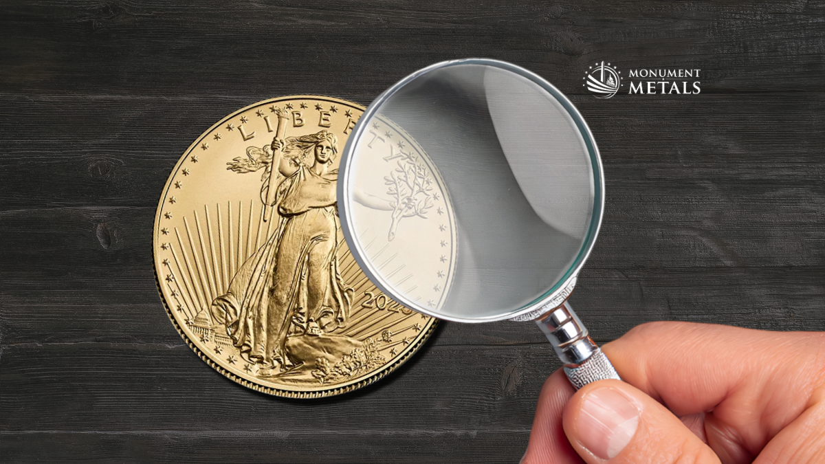 Magnifying glass held over a gold American Eagle coin on a dark wood background, highlighting inspection of design details to verify authenticity, with the Monument Metals logo in the upper right.
