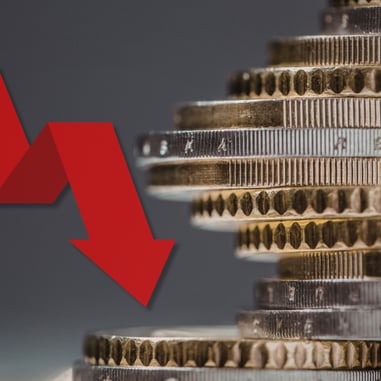 Gold and silver coin stack with red downward arrow showing gold price drop and silver market dip in precious metals market