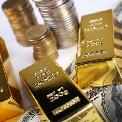 Gold bullion with gold coins and U.S. currency in the background