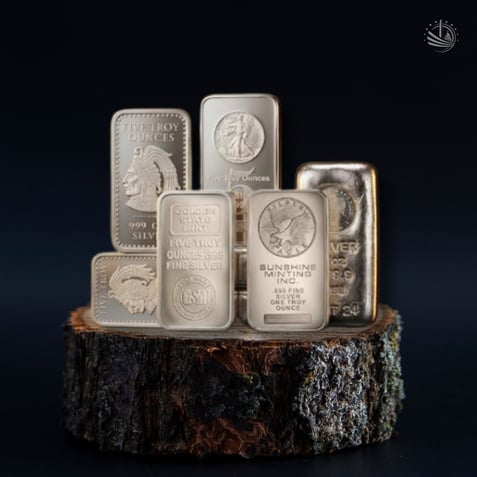 Assorted secondary market silver bars from multiple mints in varied condition displayed on a wood base against a dark background