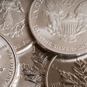 Close-up of popular silver bullion coins including American Silver Eagles and Canadian Maple Leafs, highlighting fine silver investment products.