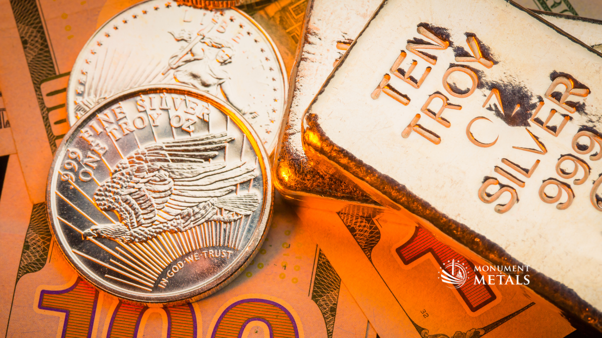 Gold and silver bullion displayed on top of $100 bills, illustrating how different dollar amounts can translate into precious metals purchases.  