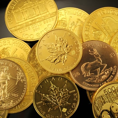 Pile of gold bullion coins including Canadian Maple Leafs, South African Kruggerands, Chinese Pandas, American Eagles, and Austrian Philharmonics 