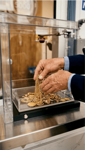Monument Metals team member placing gold chains and gold coins in a display case at our Frederick, MD location