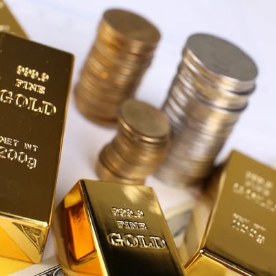 Gold bars arranged beside stacks of gold- and silver-colored coins in a precious metals portfolio.