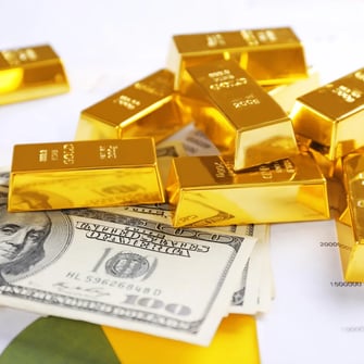 Assorted gold bars displayed over U.S. hundred-dollar bills and financial documents.